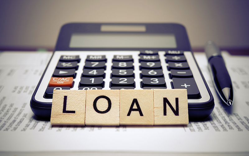 Calculator with the word loan written in wooden block letters.